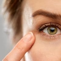 close up of woman pointing finger to eye