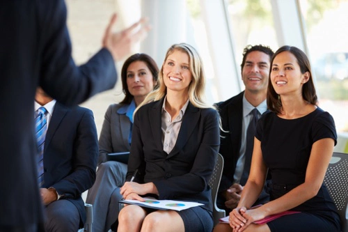 Presentation expert - David D. Doerrier speaking to a-audience-of-business-people-smiling-at-a-presenter